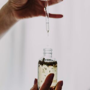Close-up of hands using a dropper with an essential oil bottle, perfect for wellness themes.